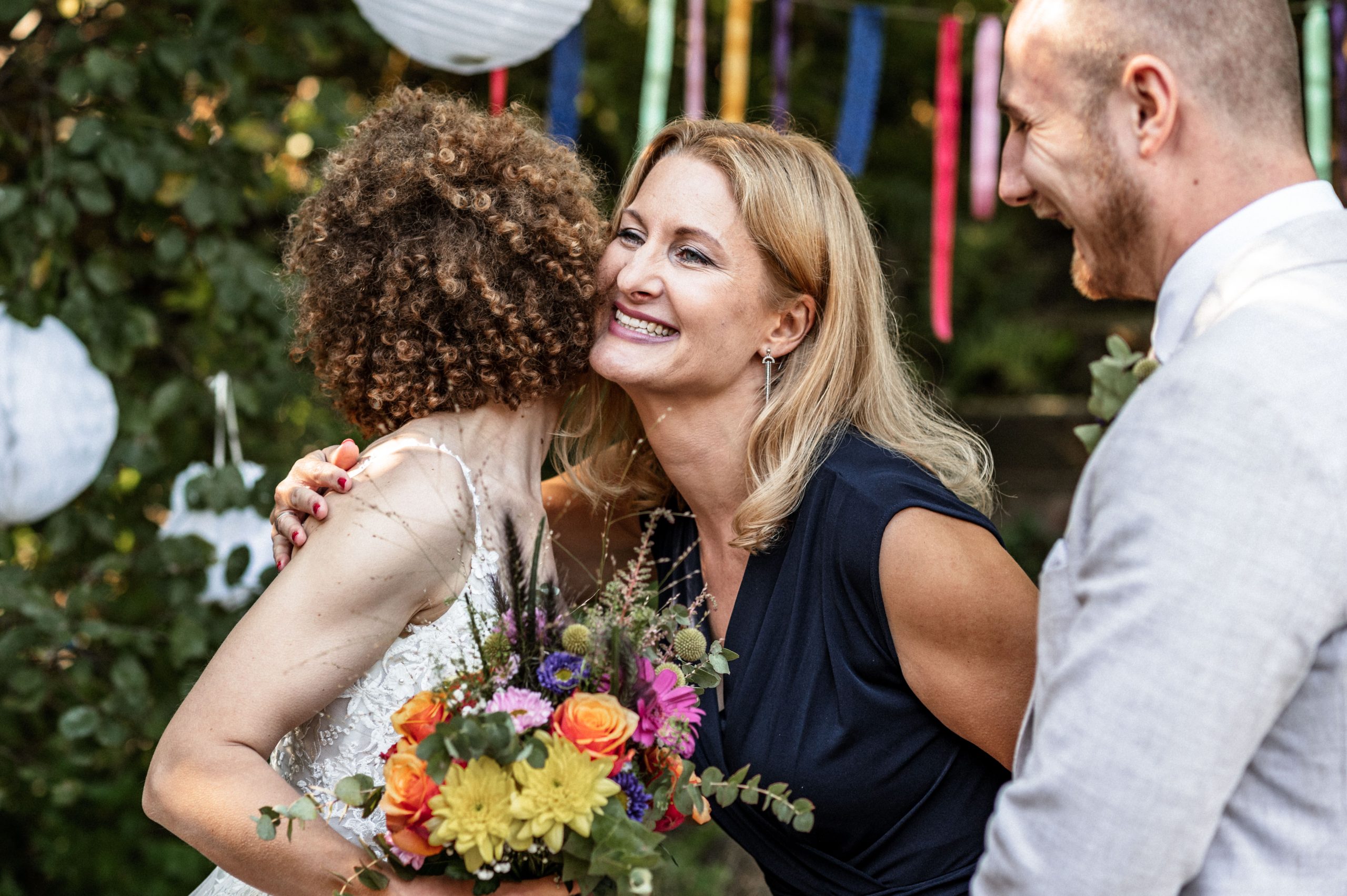 Brautpaar umarmt Traurednerin Kirsten Steinbrück von Words of Love nach der Hochzeit